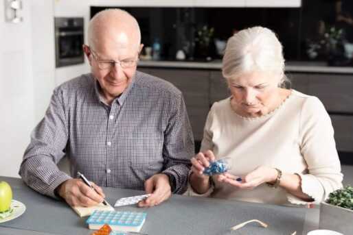 A senior man and a senior woman plan their medication for the week